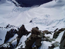 John Kazanas climbing the very last part of summit rocks with the Grand Plateau and Hochstetter Glacier below